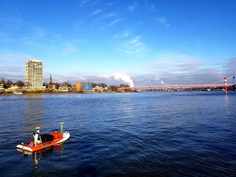 A small orange Riverdrone vessel on a river.